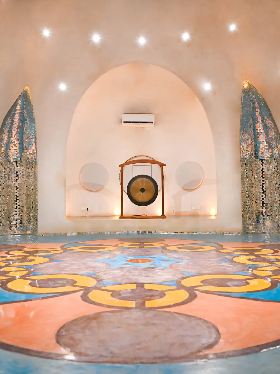 The Dome at Holistika: a white sound temple with a mandala floor and a gong