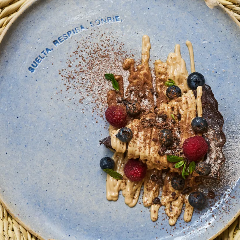 A dessert with berries on a plate that reads “suelta, respira, sonríe”