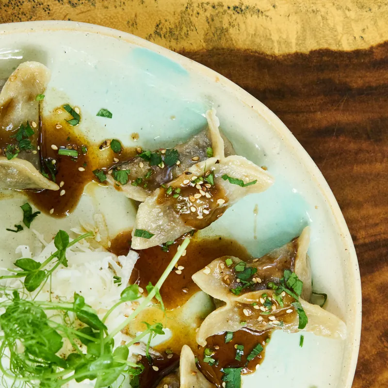 Dumplings with sesame, sauce and fresh greens