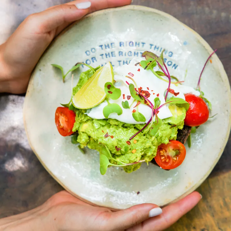 Guacamole with tomatoes and lime on a hand-thrown plate