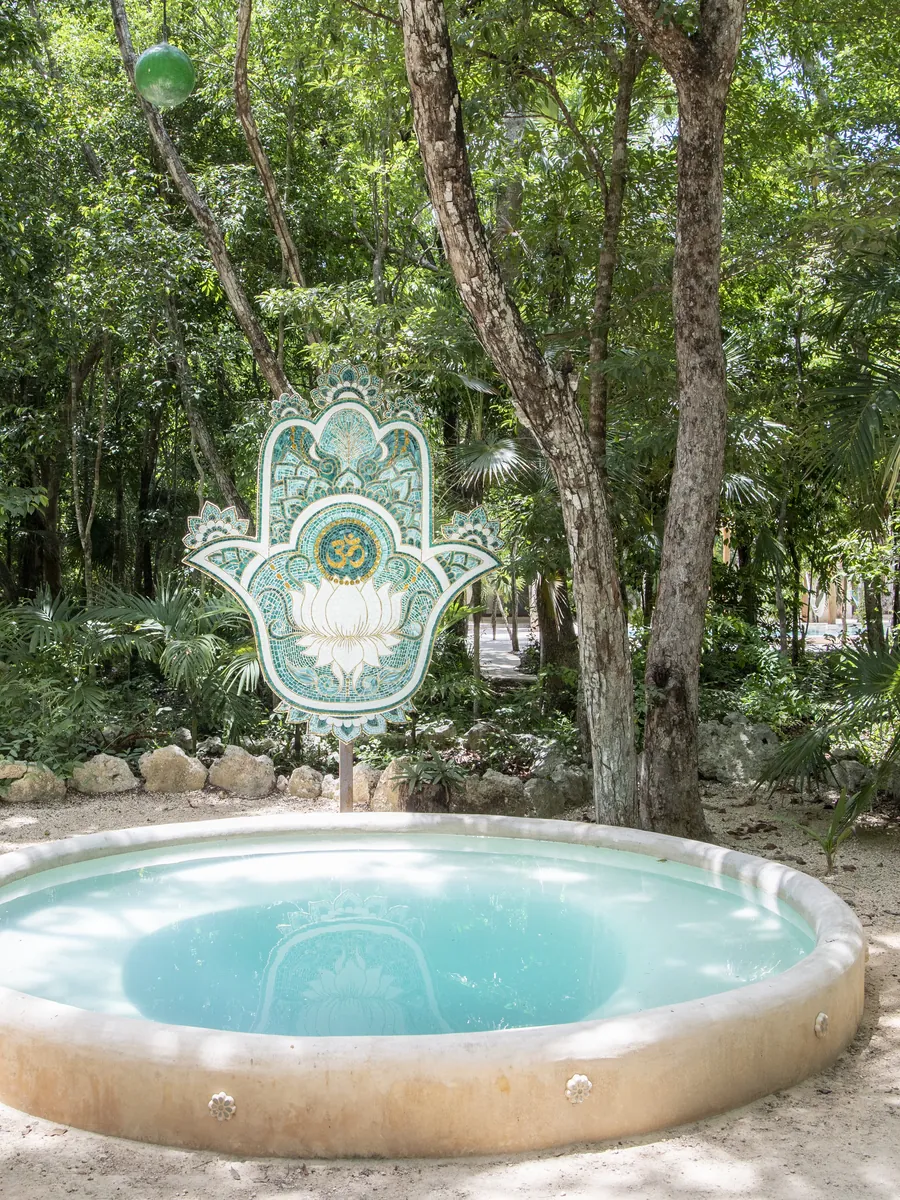 A round pool beside a hamsa sculpture on Holistika’s jungle paths