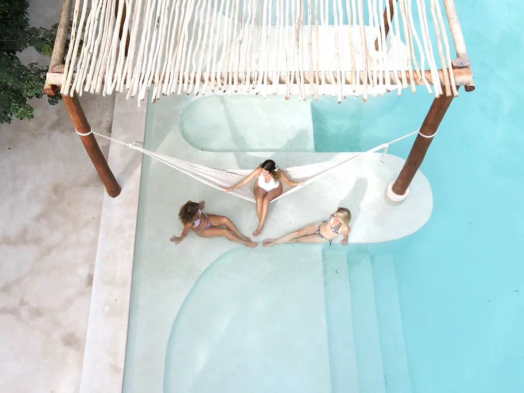 Guests resting in a hammock over the pool, from above