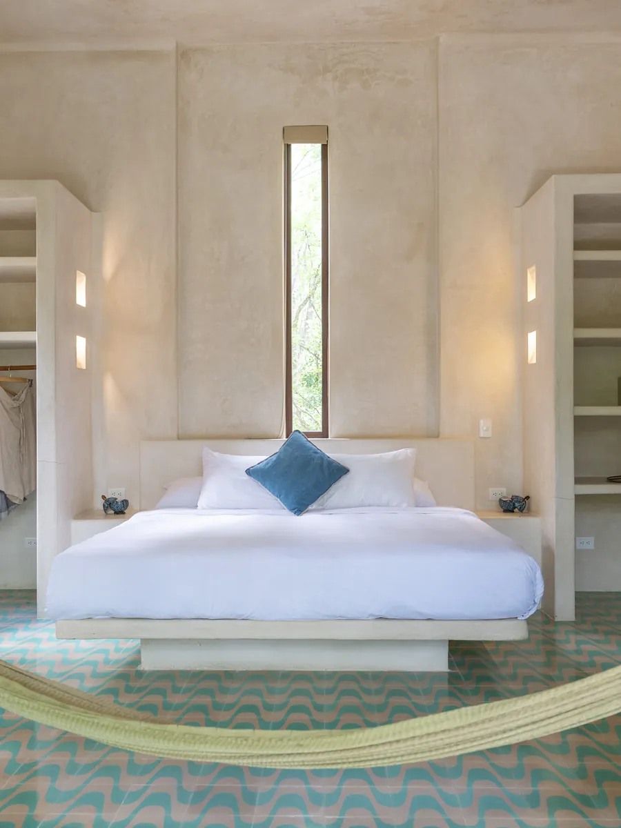 A Holistika room: white walls, turquoise tiles and a hammock