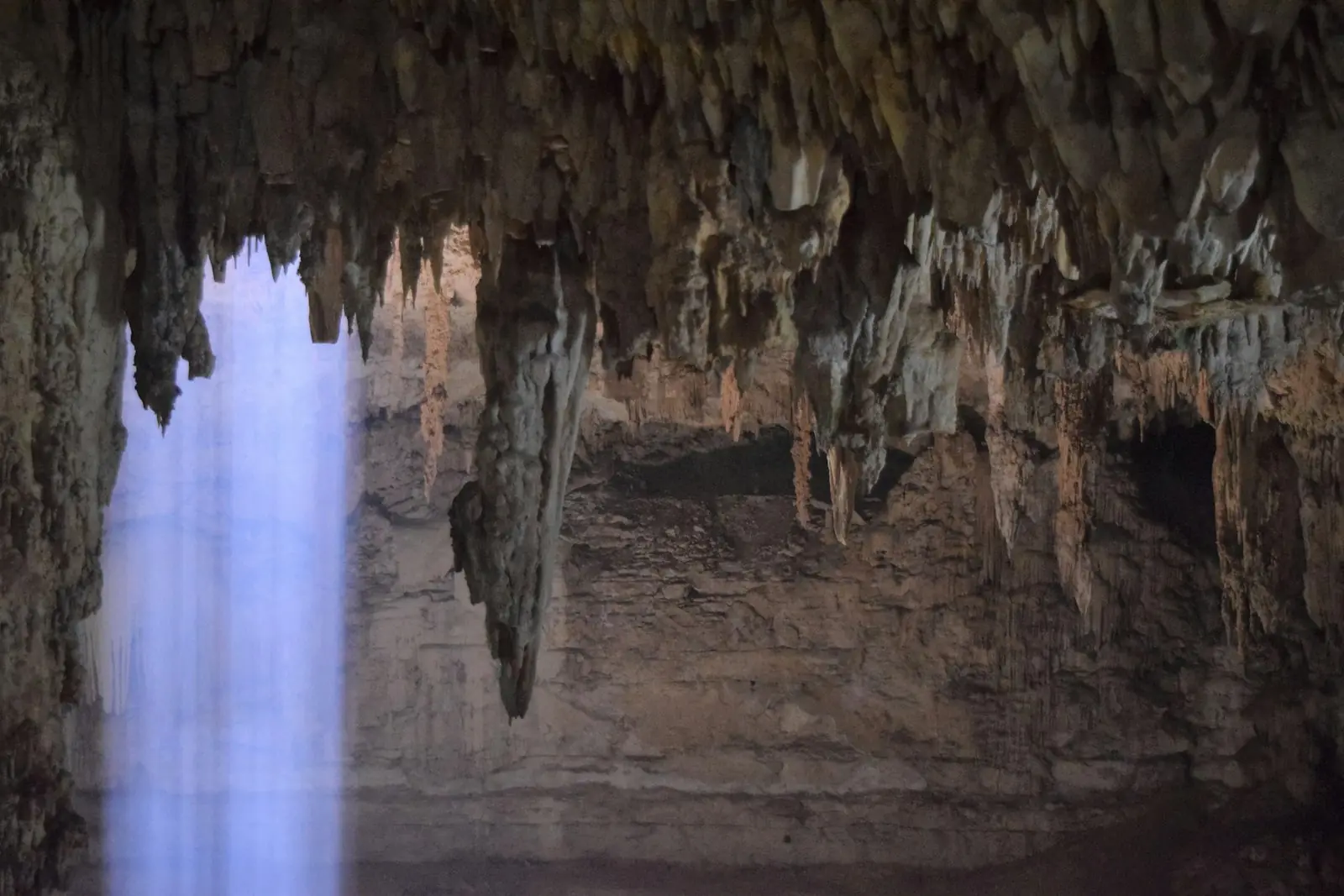 A shaft of sunlight falling into a dark cenote